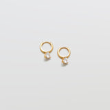 Gold CZ heart huggie earrings on white background.