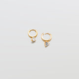 Gold huggie earrings with heart-shaped cubic zirconia accent and hinged hoop closure.