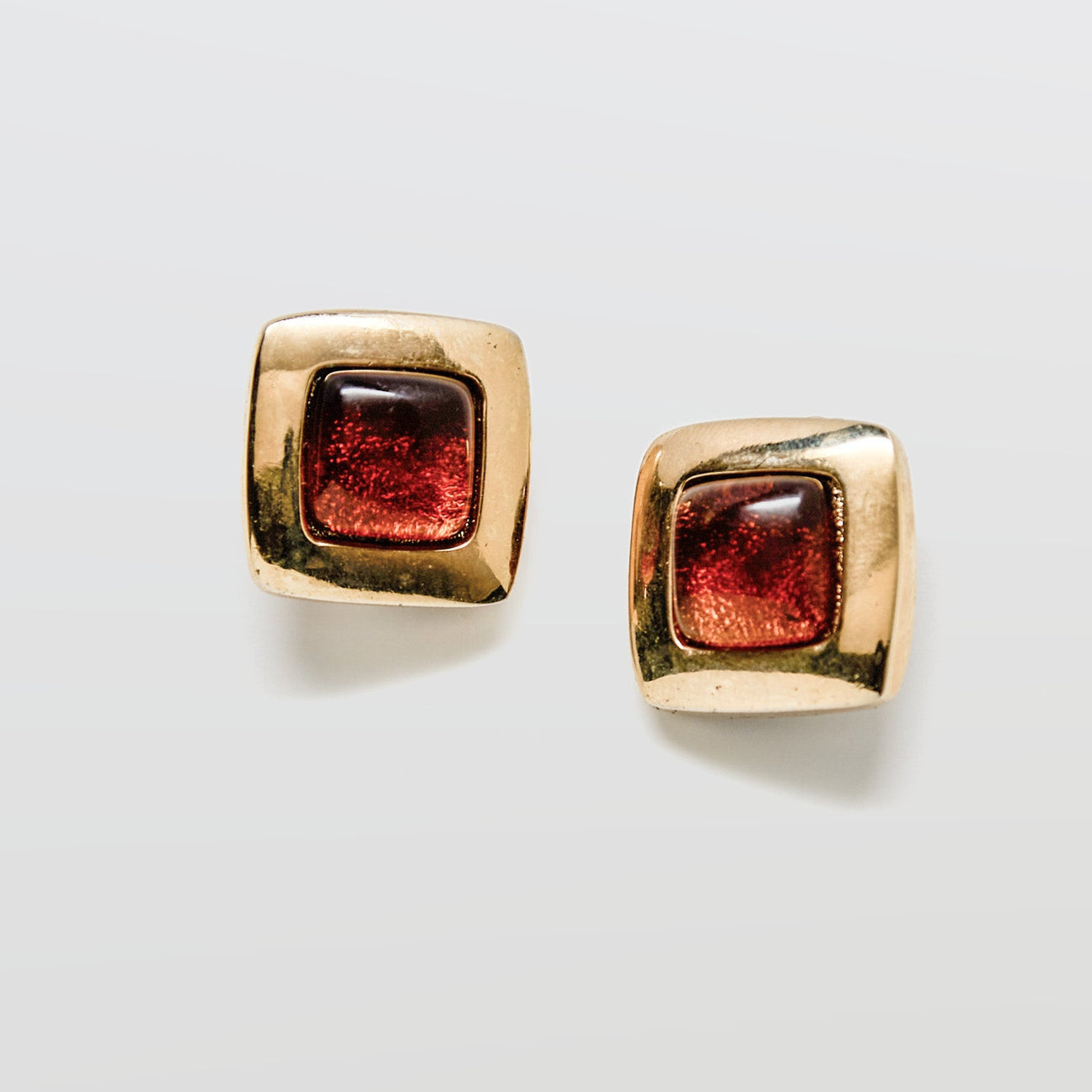 Gold square earrings with brown gemstones on a white background