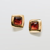 Gold square earrings with brown gemstones on a white background
