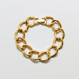 Gold chain bracelet on a light gray background