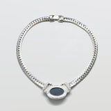 Silver chain necklace with a black stone on a light gray background