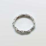 Silver ring with textured design on a light gray background